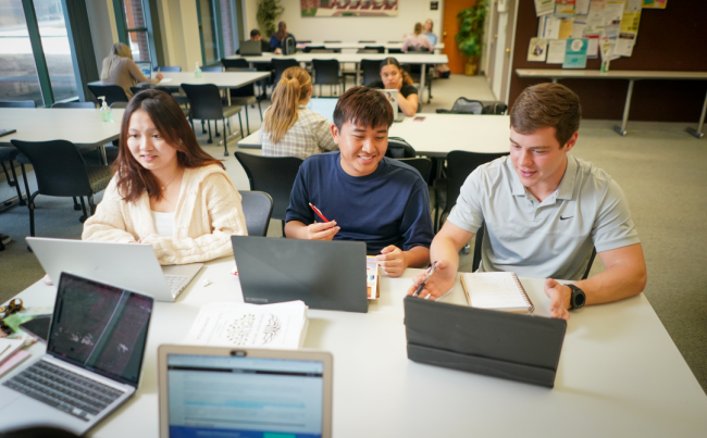 Three students work at open laptops.